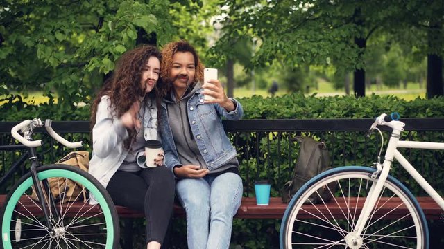 Best friends are taking selfie with smartphone posing for funny pictures making moustache from hair then hugging and taking photos. Modern lifestyle concept.