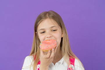 Child eat donut on violet background. Little girl bite glazed ring doughnut. Candyshop concept. Childhood and happiness. Kid with junk food. Sweet mood. Unhealthy eating and snack food