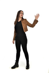 full length portrait of brunette girl wearing brown leather jacket.   standing pose on white...