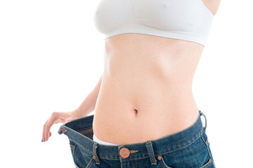 Closeup view of trained belly with big old jeans. Sport, fitness and diet concept. Isolated on white background