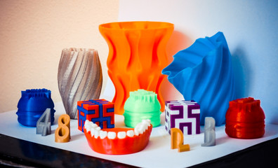 Models printed by 3d printer. Bright colorful objects printed on 3d printer on table.Automatic...