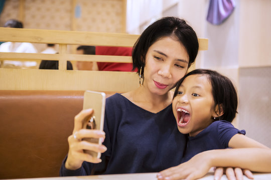 Funny child taking photo selfie with her mother