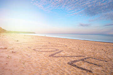 View of the sea and the beach with text LOVE on the sand.