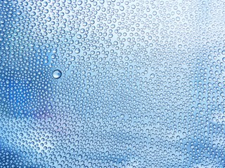 Water drops on the glass in a cool blue tones. in the rainy season. For design, textures and backgrounds.