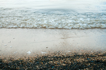 Wet sand from the waves on the shore of a forest lake