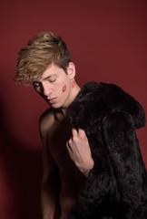 A man in black fur on red background. Sexy body