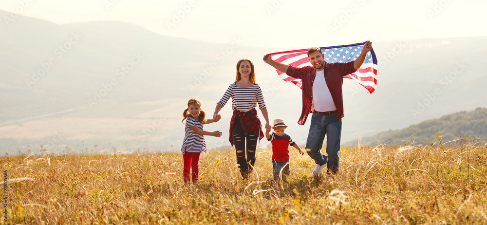 Wall mural happy family with flag of america USA at sunset outdoors