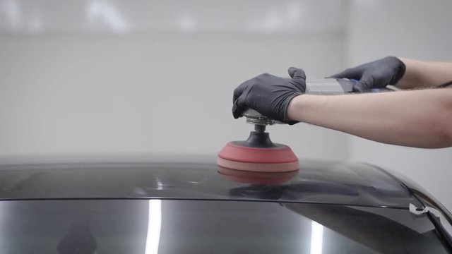 Close up shot of a man using polising machien on a car rooftop.