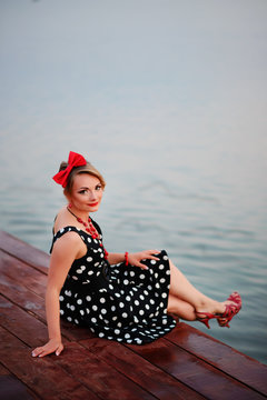 A beautiful young woman dressed sitting on the pier