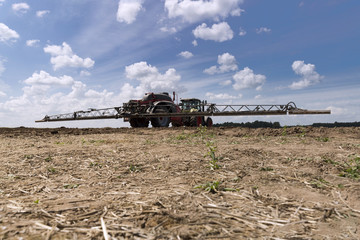 Fototapeta premium Machine for spraying pesticides and herbicides in the field against blue sky. Heavy machinery for agriculture