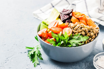 Buddha bowl with roasted root vegetables, greens, lentils, tomatoes. Selective focus, space for text.