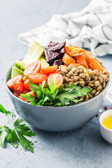 Buddha bowl with roasted root vegetables, greens, lentils, tomatoes. Selective focus, space for text.