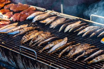 Fresh fish is grilling in 2 rows on a barbecue grill at a street market stall during winter in Melbourne Australia