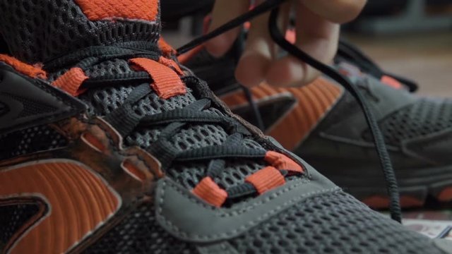 Closeup tying shoelaces on sneakers. Athlete tied up shoelaces, running shoes. Close up. Slow motion.