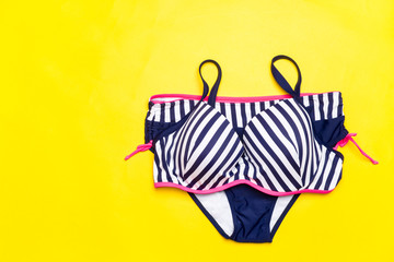 Fashion. Summer clothes, Accessories set- Trendy Swimsuit Bikini on the yellow background. Beach Outfit. Flat lay.Creative Art. Hot Vibes. Vacation and Relax Concept.Top view.