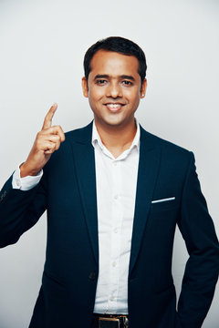 Portrait Of Smiling Indian Businessman In Suit Raising Index Finger