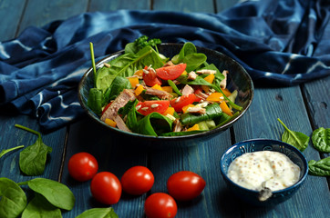 Spinach salad with cherry tomatoes. Mustard sauce in a small bowl