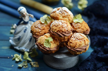 Little profiteroles with chocolate cream on a blue wooden background