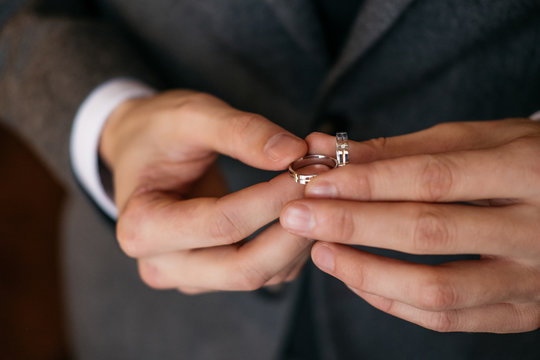 Groom holds in his hands two wedding rings