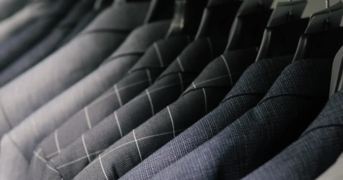 Men's suit at tailor's shop. Men's hands choose a jacket in their wardrobe. Male choosing