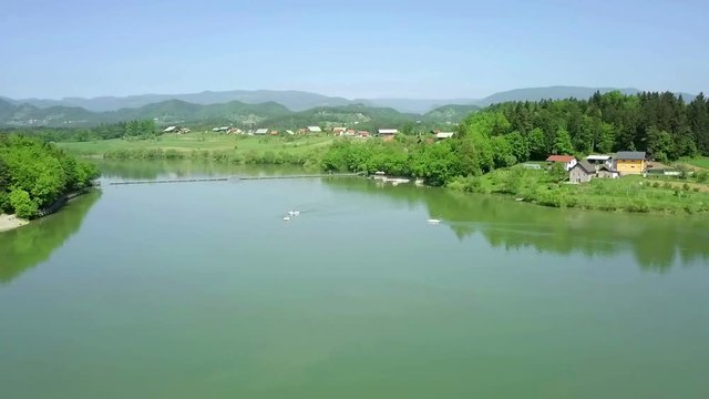 Aerial: Flying over green lake with few pedaling boats on it on sumer sunny day. Flying with drone and filming on beautiful sunny summer day.
