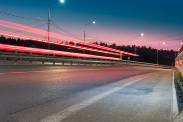 Obraz premium The car light trails on the road with metal safety barrier or rail