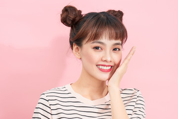 Portrait of funny young pretty girl with two buns making gesture hand over pink background.