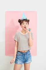 Profile portrait of teenage girl in cap blowing in party horn blower