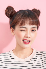 Portrait of cool carefree asian woman with bun hairstyle, being confident in her beauty and standing over pink wall