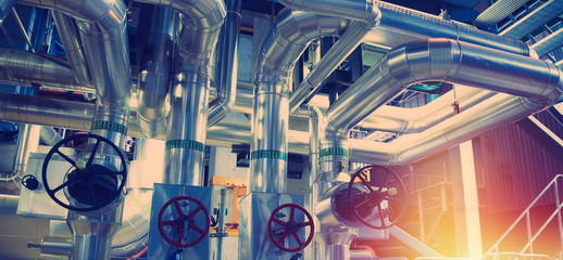 Equipment, cables and piping as found inside of a modern industrial power plant. Industrial zone, Steel pipelines, valves, cables and walkways