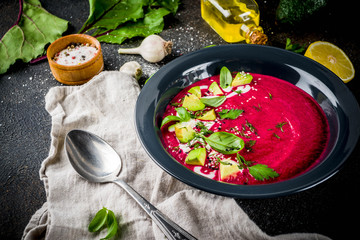 Vegan food, summer cold Beetroot gazpacho soup with lemon, avocado and fresh herbs copy space top view