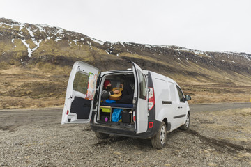 Iceland, man lying in van playing guitar