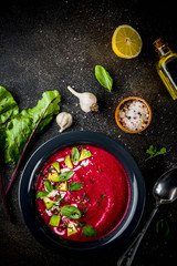 Vegan food, summer cold Beetroot gazpacho soup with lemon, avocado and fresh herbs copy space top view