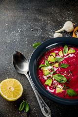 Vegan food, summer cold Beetroot gazpacho soup with lemon, avocado and fresh herbs copy space top view