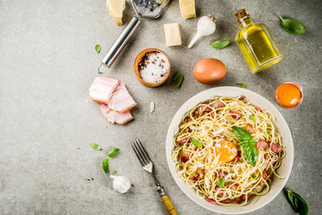 Traditional italian pasta, spaghetti carbonara with bacon, creamy sauce, parmesan cheese, egg yolk and fresh basil leaves grey stone background copy space