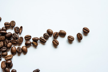 Fried coffee grains lie on a light surface on the table.