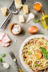 Traditional italian pasta, spaghetti carbonara with bacon, creamy sauce, parmesan cheese, egg yolk and fresh basil leaves grey stone background copy space