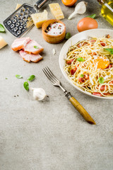 Traditional italian pasta, spaghetti carbonara with bacon, creamy sauce, parmesan cheese, egg yolk and fresh basil leaves grey stone background copy space