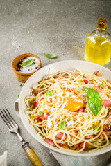 Traditional italian pasta, spaghetti carbonara with bacon, creamy sauce, parmesan cheese, egg yolk and fresh basil leaves grey stone background copy space