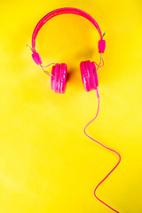 Bright pink headphones  on yellow background