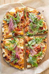 Wood fired pizza with tomato sauce, mozzarella, marinated cherry tomatoes, topped with rocket and parma ham. 