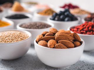 Almond in small white bowl and other superfoods on background. Selective focus. Different superfoods ingredients. Concept and illustration for superfood and detox food