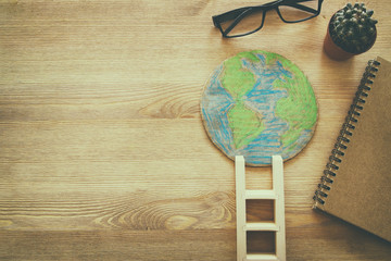 top view image of earth globe and ladder over wooden background.