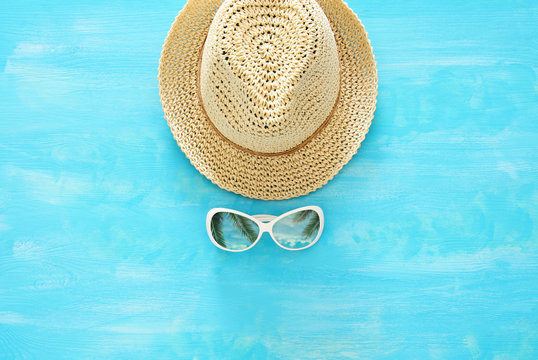 vacation and summer image with fedora beach hat and sunglasses over blue wooden background.