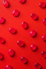 top view of collection of candies on red surface with water drops