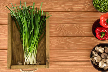 top view of leeks in box and various vegetables on wooden tabletop