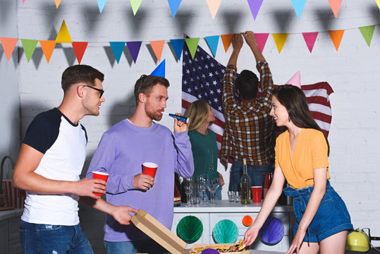 happy young male and female friends smiling each other while having fun and partying together