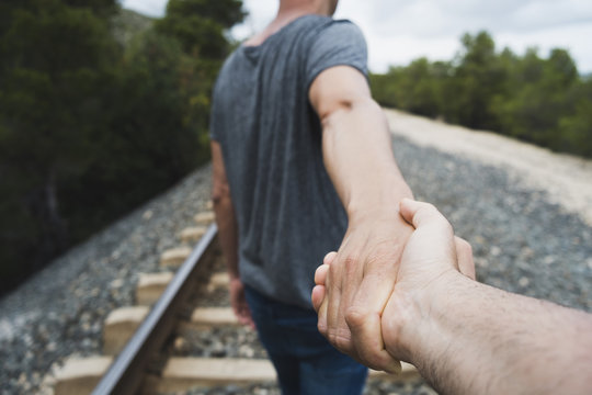men holding hands on the railroad tracks