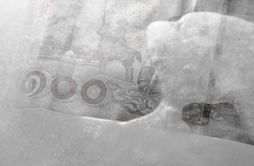 Thai banknote freezing in ice on plastic tray