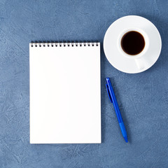 open notepad with clean white page, pen and coffee cup on aged dark blue stone table, top view